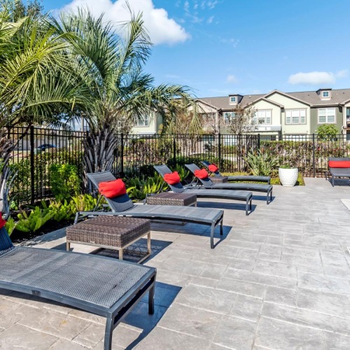 a pool with chairs and tables by it and trees in the back